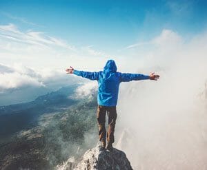 Mann auf dem Gipfel umarmt die Welt